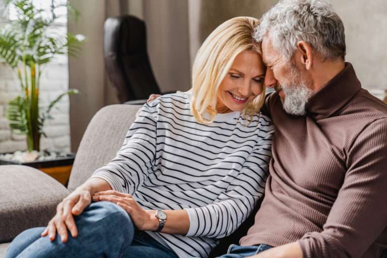 Retirement Planning - Joyful middle aged couple relaxing and hugging at home